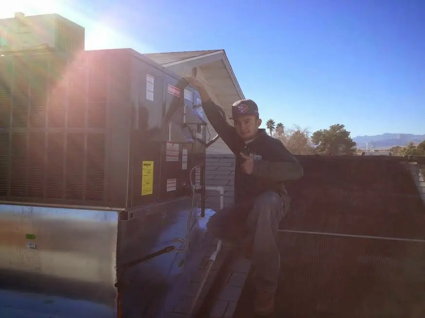 HVAC technician performing AC Tune-Up on a rooftop unit in West Little River